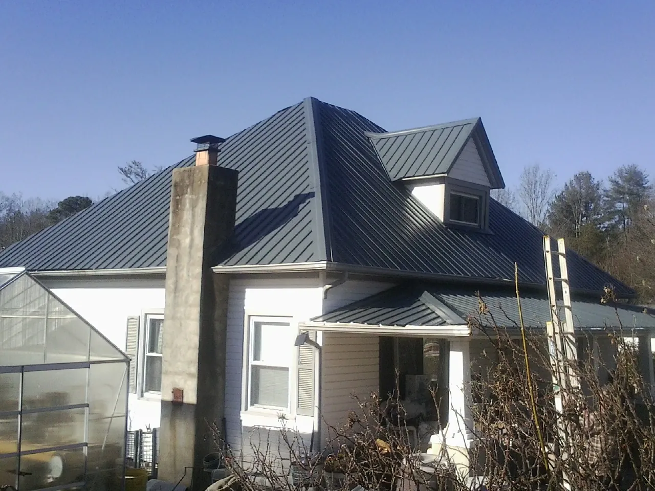 Dark blue standing seam metal roof on a white farmhouse with dormer — Slate & Tile Roof Repair by Roofing Brothers in Ledgewood