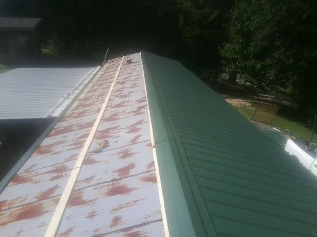 Old rusted panels beside newly installed green metal roofing — Wind Damage Roof Repair by Roofing Brothers in Ledgewood