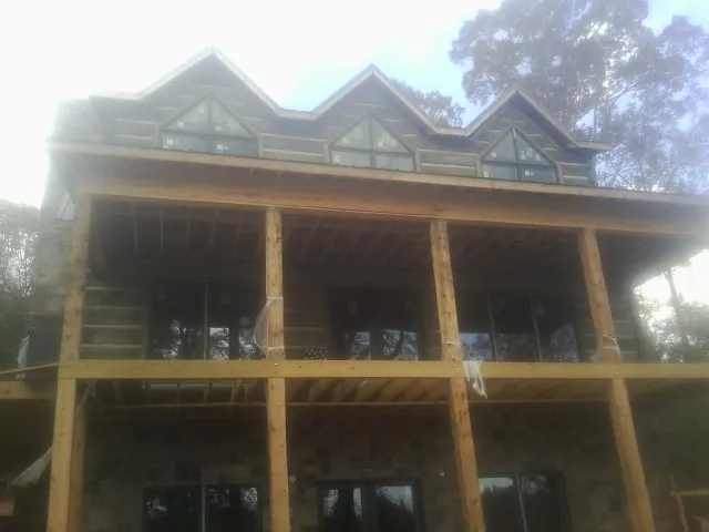 Dormers and porch framing on a large log home under construction — Roof Coating work by our crew in Ledgewood