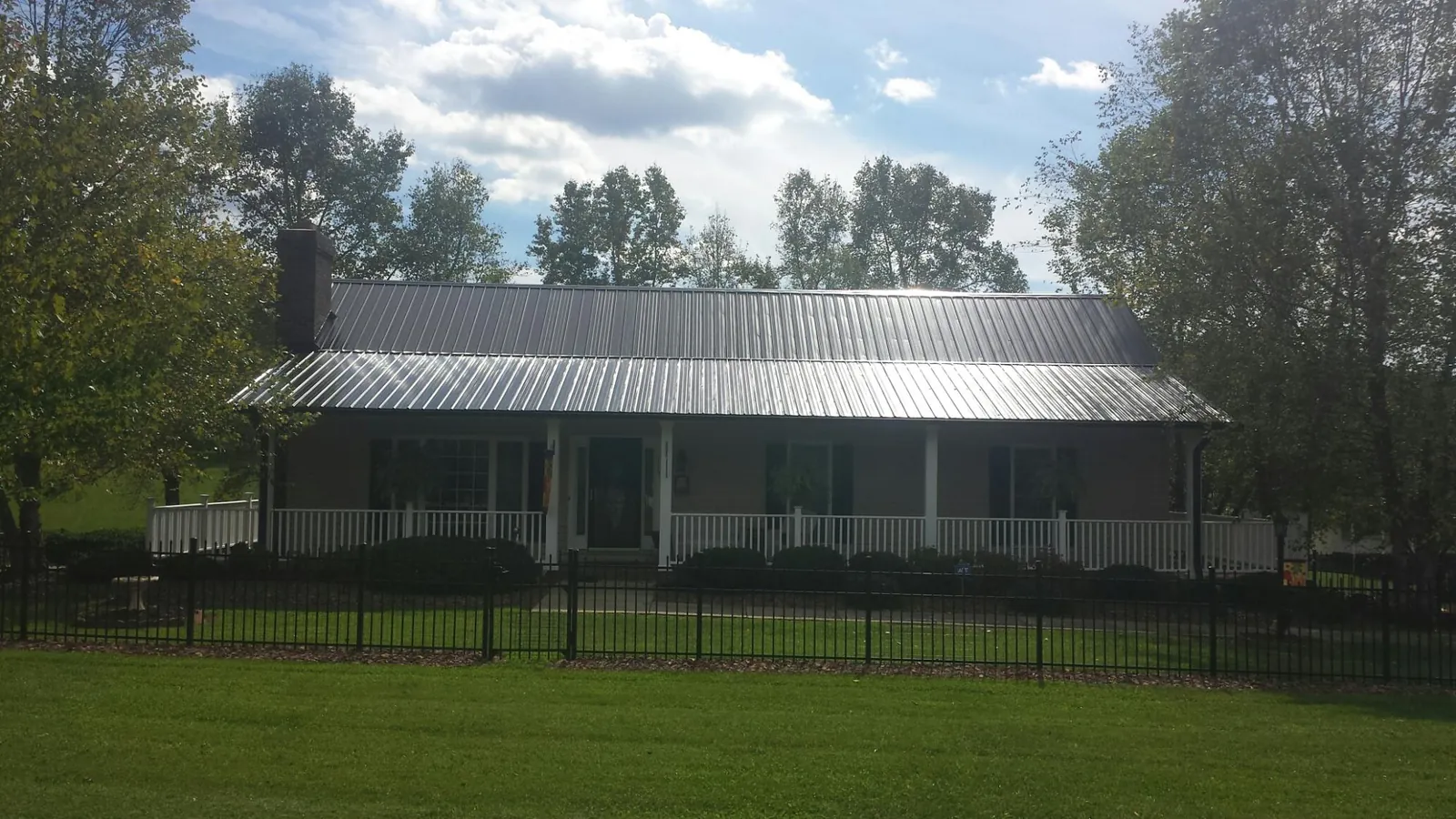 Gray metal roof on a brick ranch with a full width front porch — Gutter Guard Installation work by our crew in Ledgewood