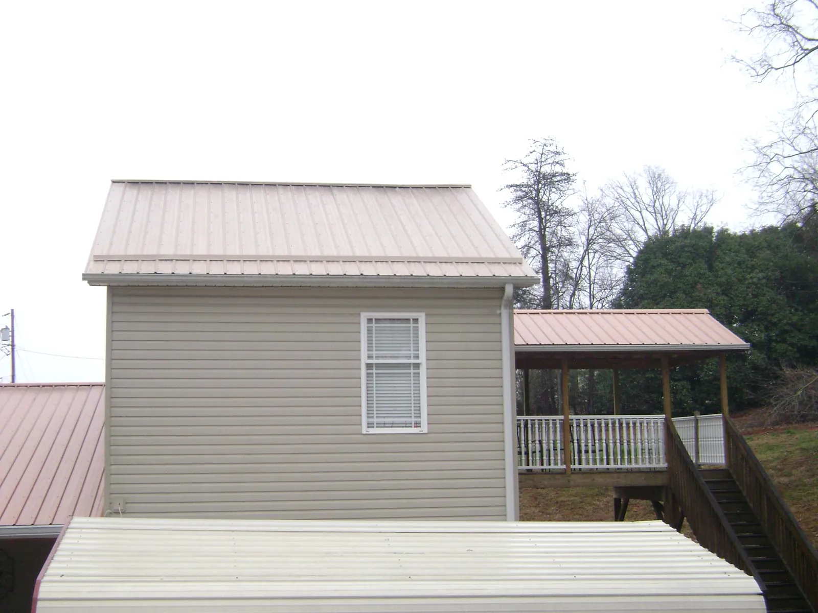 Tan metal roofs on a two story addition and attached porch, from a Roof Replacement job in Ledgewood