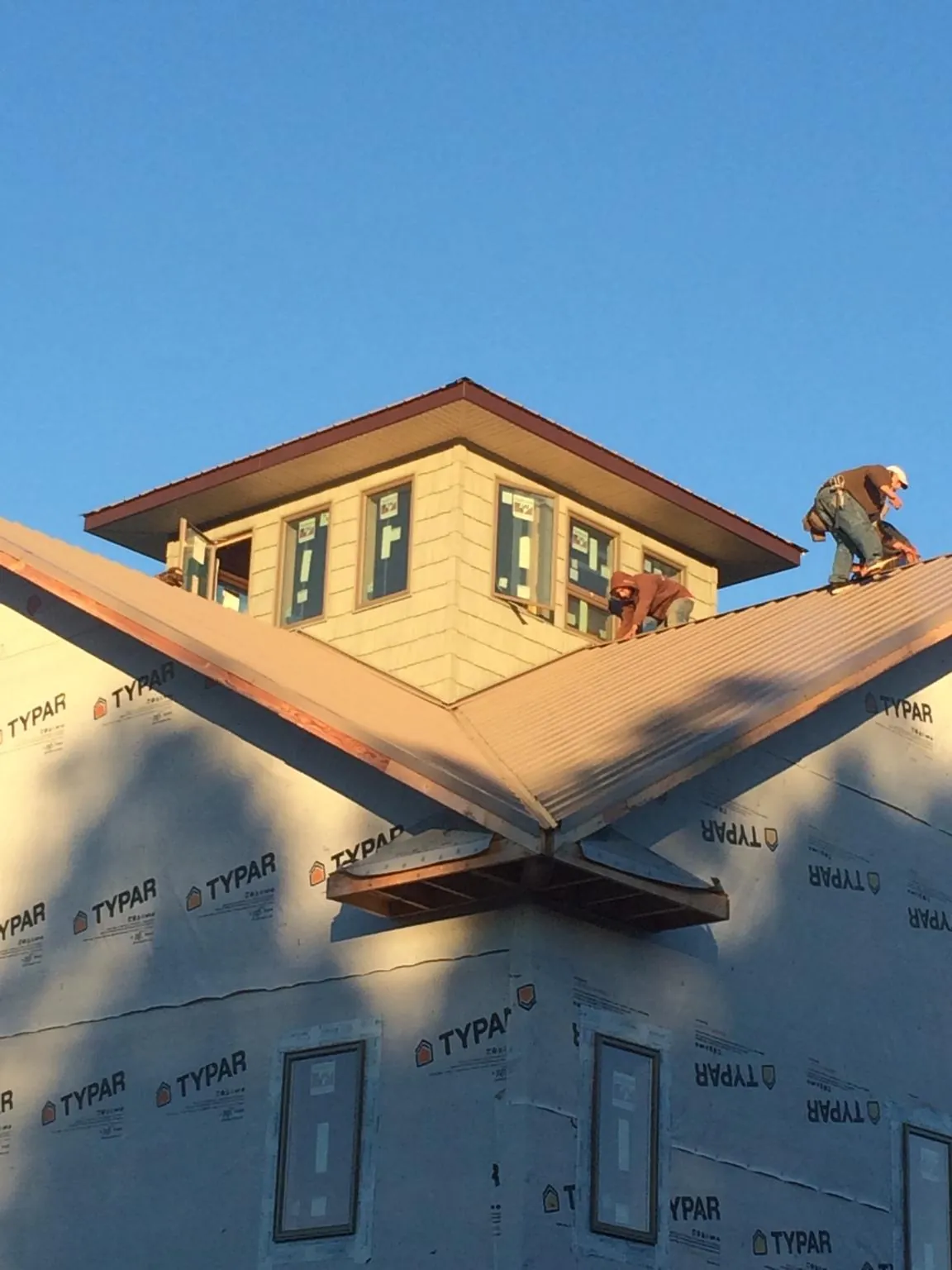 Roofers working around a rooftop cupola on a new metal roof at sunset — Roof Waterproofing in Ledgewood by Roofing Brothers